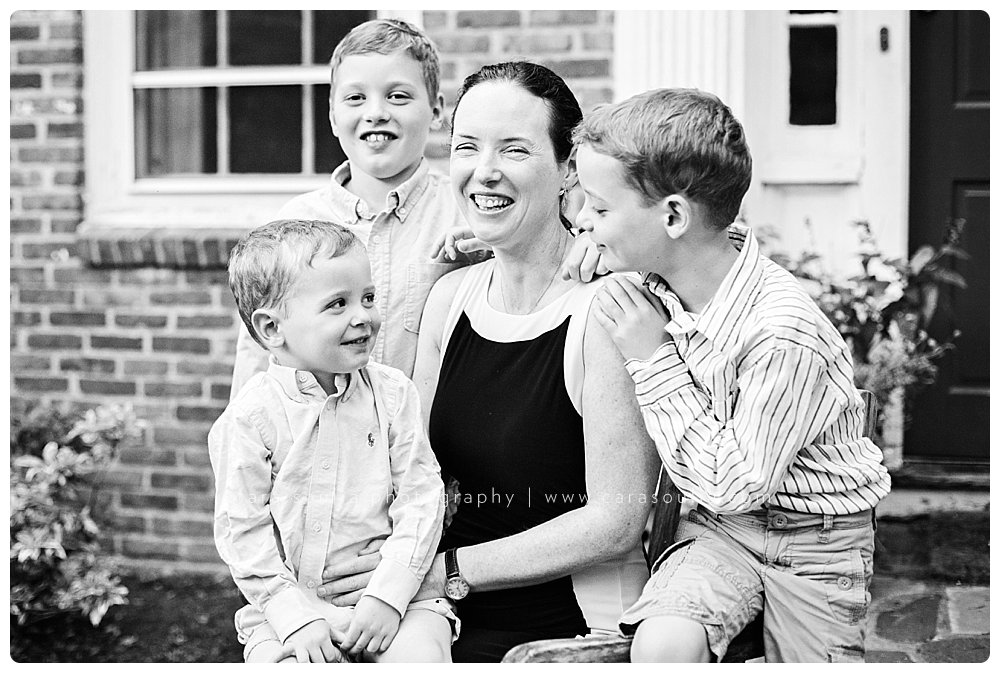 Beautiful mother and three sons sitting together on chair for a photo.