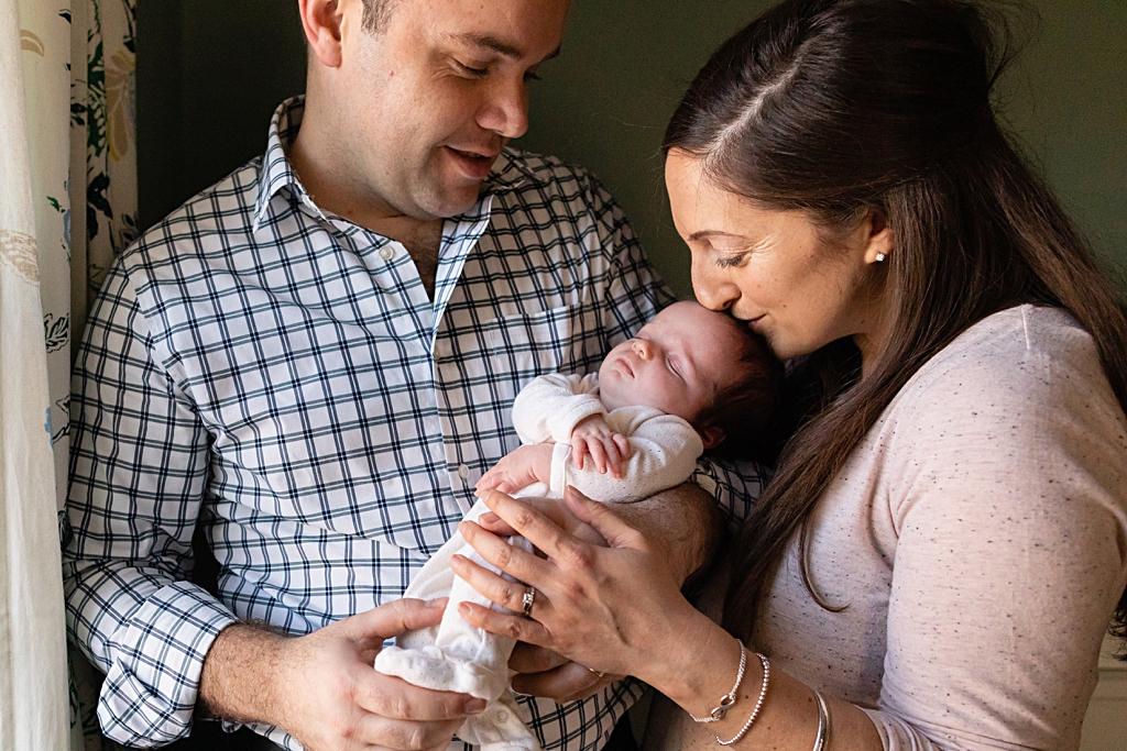 parents kissing baby at a boston newborn photo session